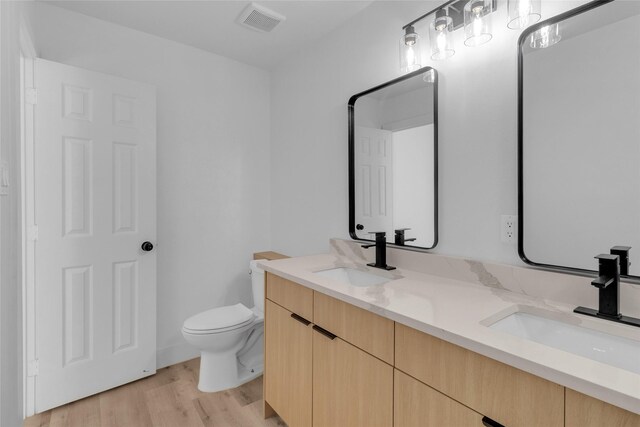 bathroom with hardwood / wood-style floors, vanity, and toilet