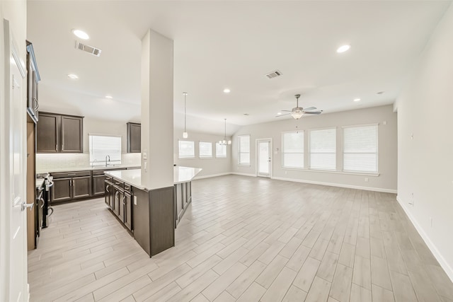 kitchen featuring stainless steel stove, light hardwood / wood-style floors, dark brown cabinets, and a kitchen island