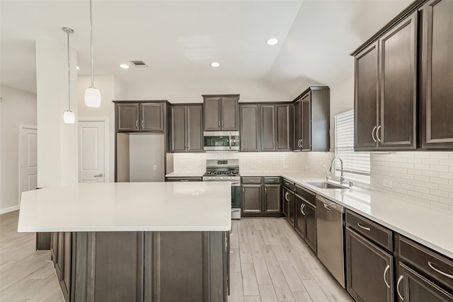 kitchen featuring sink, appliances with stainless steel finishes, light hardwood / wood-style flooring, pendant lighting, and decorative backsplash