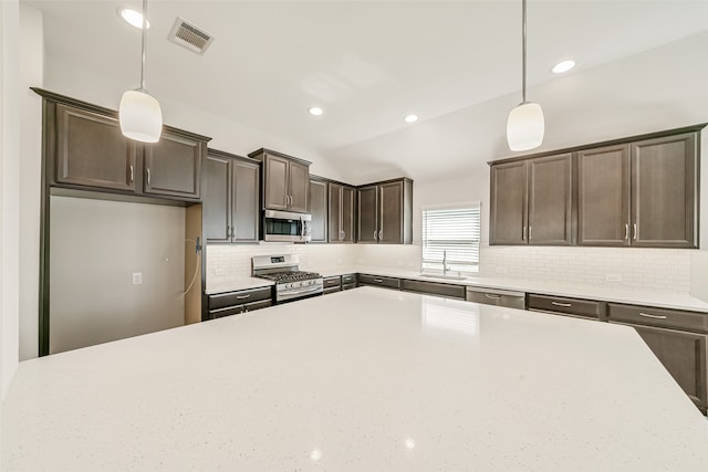 kitchen with pendant lighting, stainless steel appliances, sink, and dark brown cabinetry