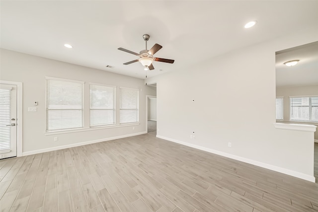 unfurnished living room featuring a wealth of natural light, ceiling fan, and light wood-type flooring