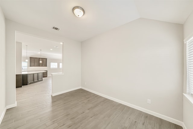 spare room featuring light hardwood / wood-style flooring and vaulted ceiling