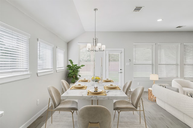 dining area featuring light wood-type flooring, lofted ceiling, and an inviting chandelier