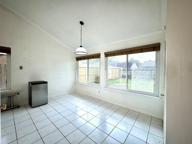 unfurnished dining area with a textured ceiling, lofted ceiling, and light tile patterned floors