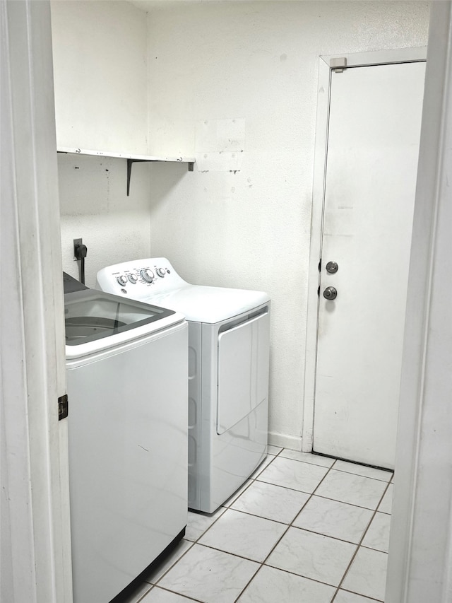 laundry area with independent washer and dryer and light tile patterned floors