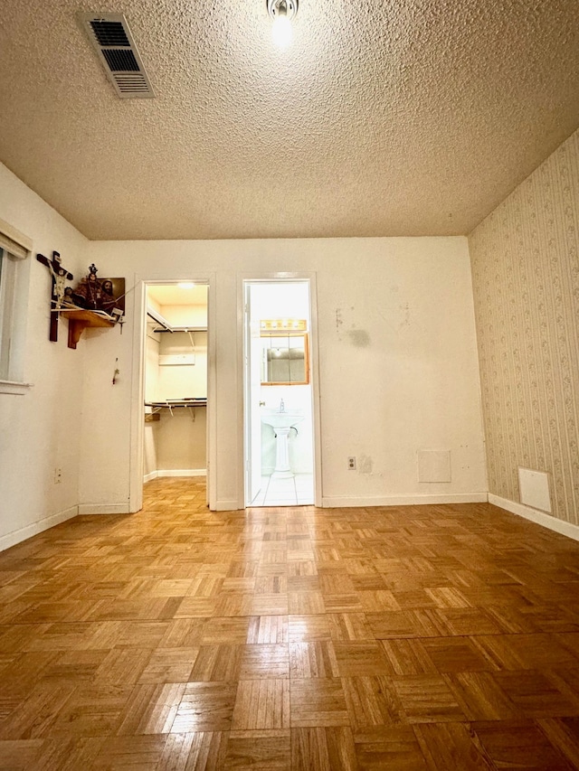 unfurnished room featuring parquet floors and a textured ceiling