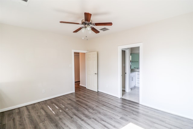 unfurnished bedroom with ensuite bath, ceiling fan, and hardwood / wood-style flooring