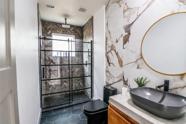 bathroom with a tile shower, vanity, tile walls, tile patterned flooring, and toilet