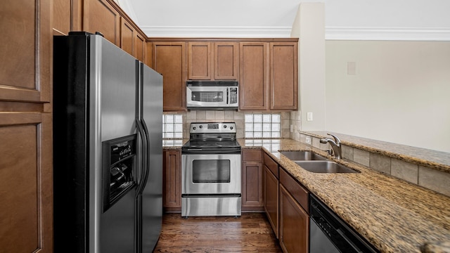 kitchen with light stone countertops, appliances with stainless steel finishes, ornamental molding, sink, and dark hardwood / wood-style floors