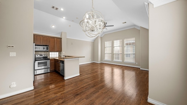 kitchen with dark hardwood / wood-style flooring, kitchen peninsula, appliances with stainless steel finishes, and vaulted ceiling