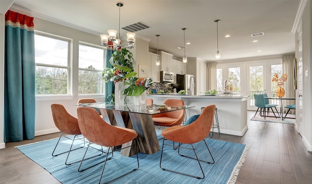 dining area featuring hardwood / wood-style floors, crown molding, and a chandelier