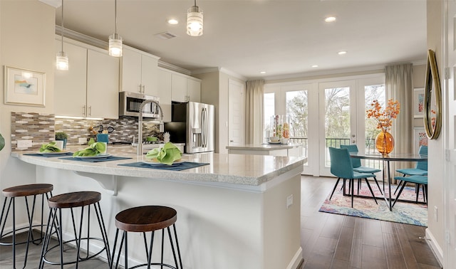 kitchen featuring white cabinets, decorative light fixtures, stainless steel appliances, and dark wood-type flooring