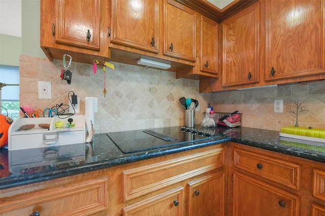 kitchen featuring decorative backsplash, dark stone countertops, and black cooktop