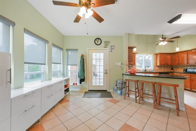 interior space featuring plenty of natural light, light tile patterned flooring, lofted ceiling, and sink