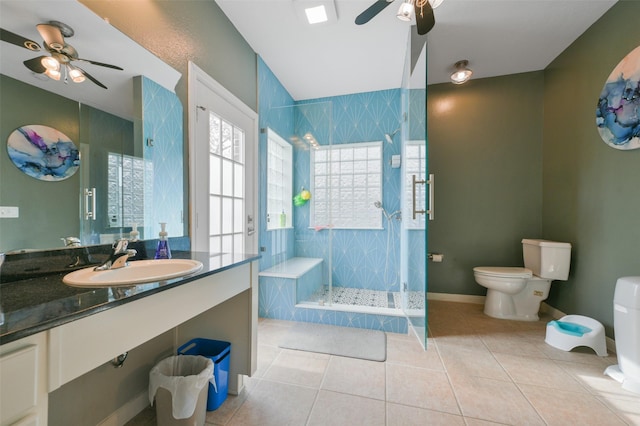 bathroom featuring tile patterned floors, ceiling fan, sink, tiled shower, and toilet