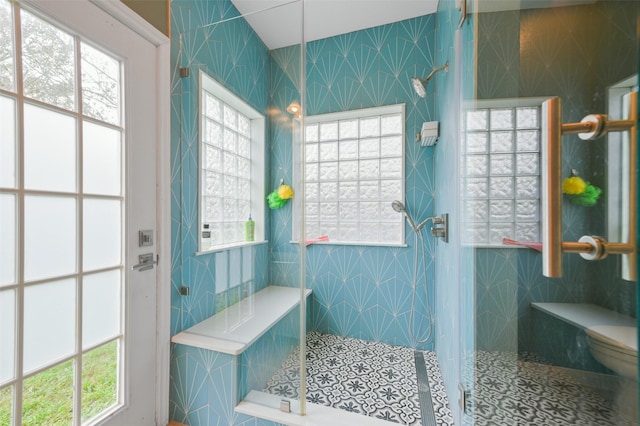 bathroom with tile patterned flooring, toilet, and a tile shower