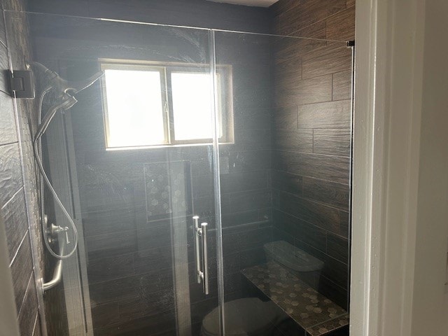 bathroom with a shower with shower door and toilet