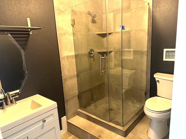 bathroom with walk in shower, vanity, toilet, and tile patterned floors