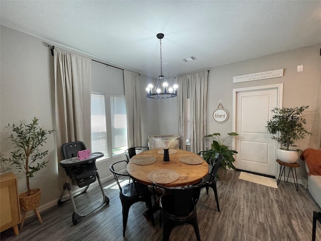 dining room with dark hardwood / wood-style floors, a textured ceiling, and a notable chandelier