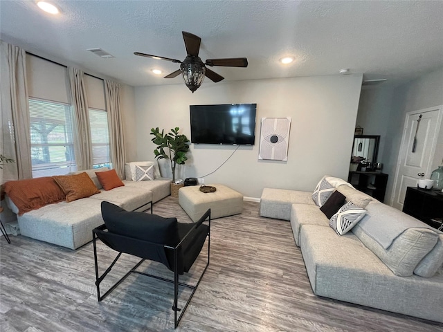 living room with hardwood / wood-style floors, ceiling fan, and a textured ceiling