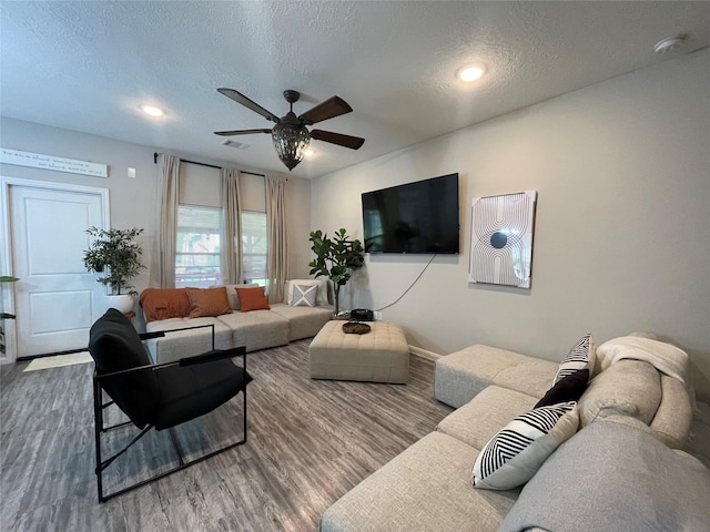 living room featuring hardwood / wood-style flooring, a textured ceiling, and ceiling fan