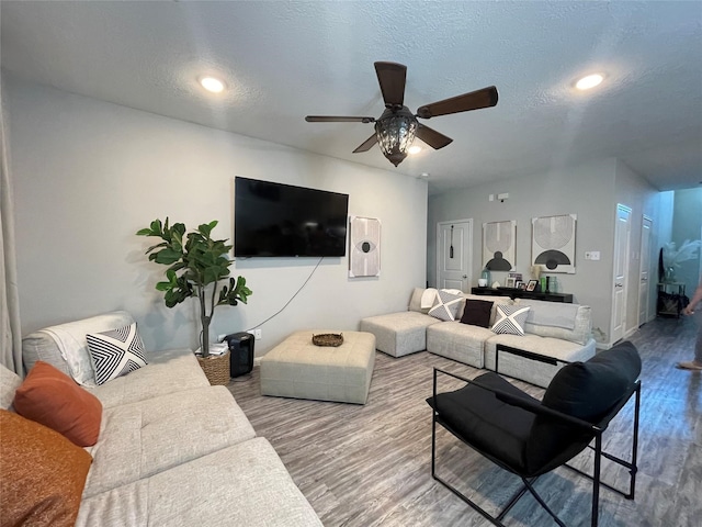 living room with hardwood / wood-style floors, ceiling fan, and a textured ceiling