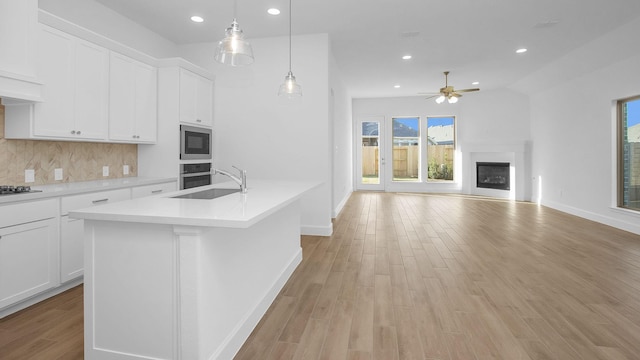 kitchen featuring white cabinetry, sink, backsplash, and a kitchen island with sink