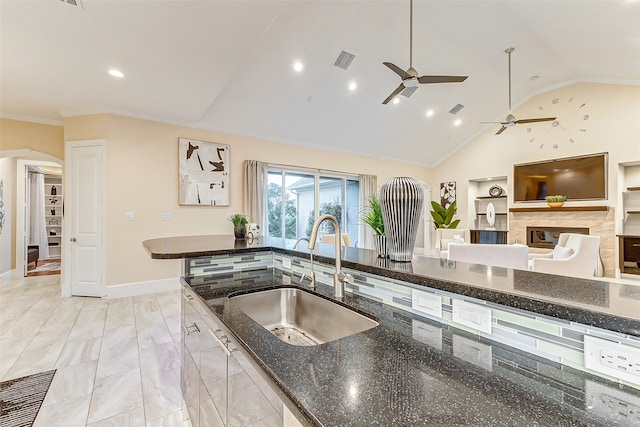 kitchen featuring ornamental molding, high vaulted ceiling, sink, dark stone countertops, and ceiling fan