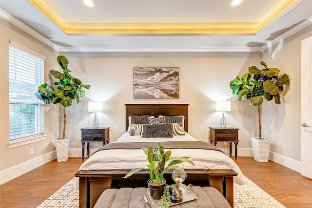 bedroom featuring hardwood / wood-style floors, crown molding, and a tray ceiling