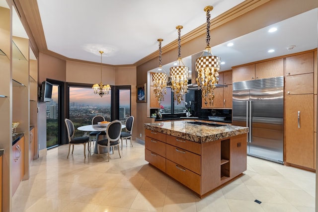 kitchen featuring built in fridge, pendant lighting, an inviting chandelier, and crown molding