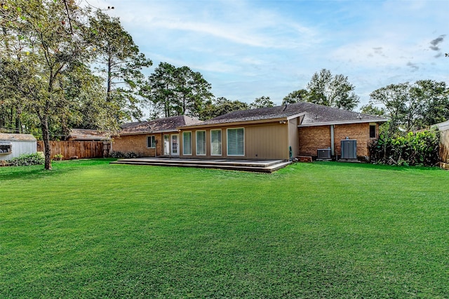 rear view of property featuring a yard, an outbuilding, fence, and a deck