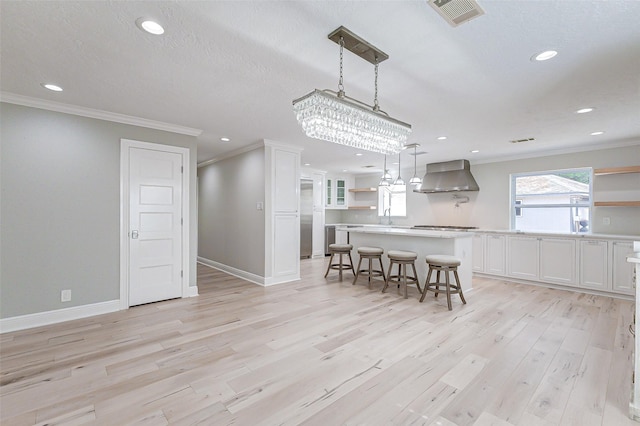 kitchen featuring visible vents, white cabinetry, wall chimney range hood, open shelves, and light wood finished floors