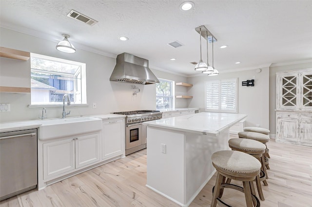 kitchen featuring open shelves, wall chimney range hood, a sink, and appliances with stainless steel finishes