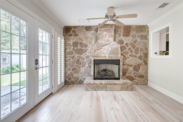 unfurnished living room featuring visible vents, ornamental molding, wood finished floors, a stone fireplace, and french doors