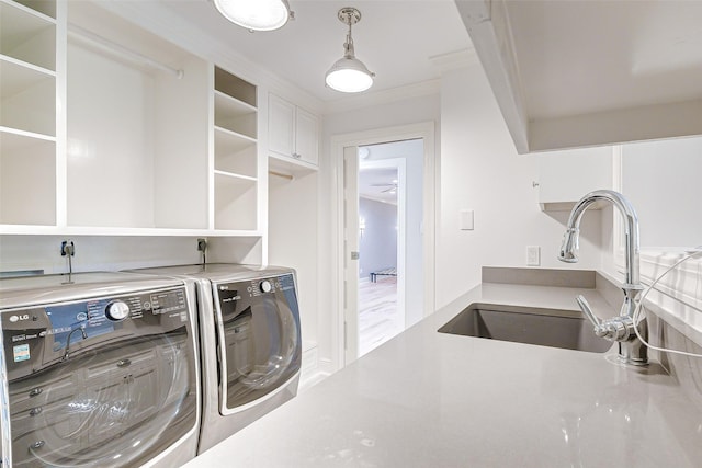 laundry room featuring a sink, cabinet space, crown molding, and washer and dryer