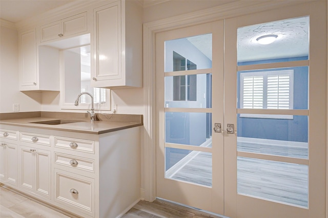 kitchen featuring french doors, white cabinets, and a sink