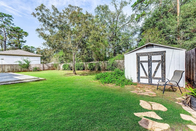 view of yard with a storage shed, a fenced backyard, and an outbuilding