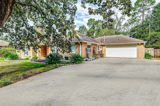 ranch-style home featuring aphalt driveway, an attached garage, fence, and brick siding