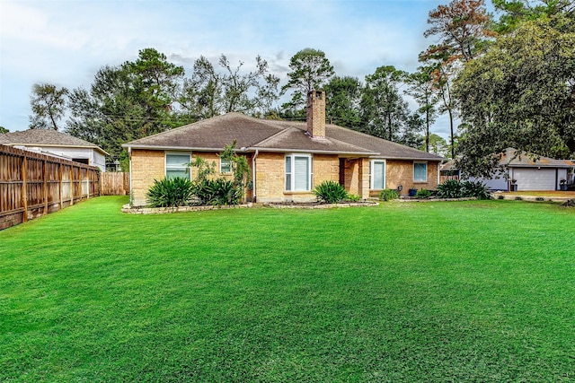 back of property with a chimney, fence, a lawn, and brick siding