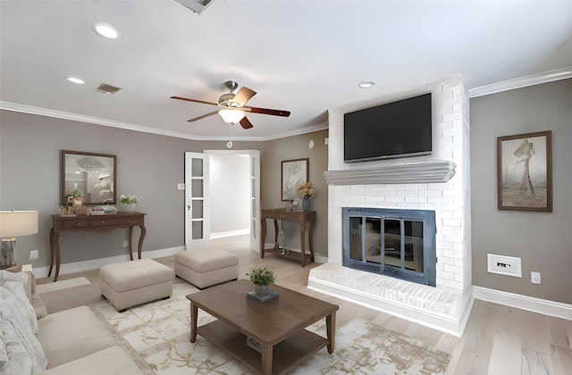 living room featuring a brick fireplace, ornamental molding, and wood finished floors