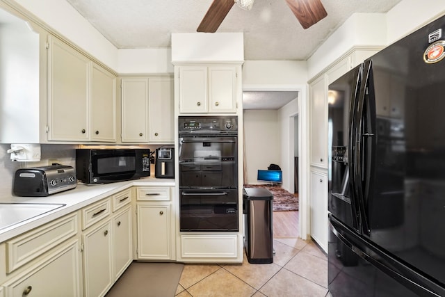 kitchen with light tile patterned floors, black appliances, and cream cabinets