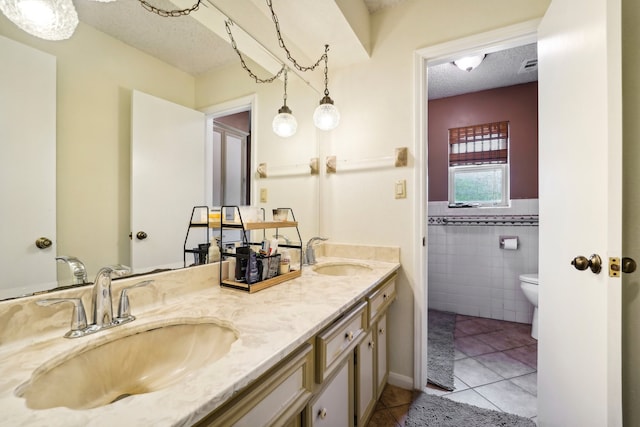 bathroom with vanity, tile patterned flooring, a textured ceiling, and tile walls