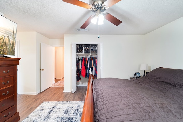 bedroom with light hardwood / wood-style floors, ceiling fan, a textured ceiling, and a closet