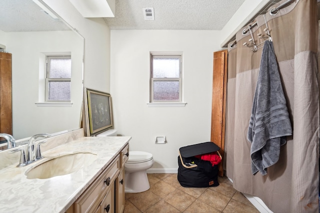 bathroom with toilet, vanity, a textured ceiling, and tile patterned floors