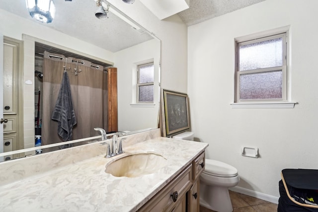 bathroom featuring a textured ceiling, tile patterned flooring, vanity, and a healthy amount of sunlight