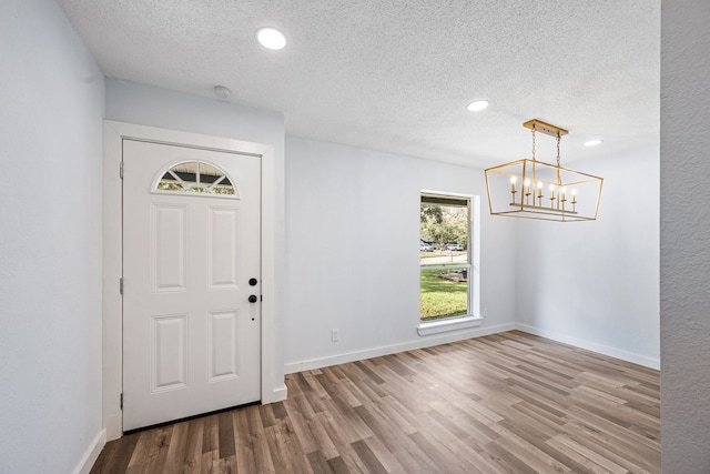 entryway with hardwood / wood-style floors, a notable chandelier, and a textured ceiling