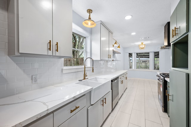 kitchen with backsplash, appliances with stainless steel finishes, pendant lighting, light stone countertops, and sink