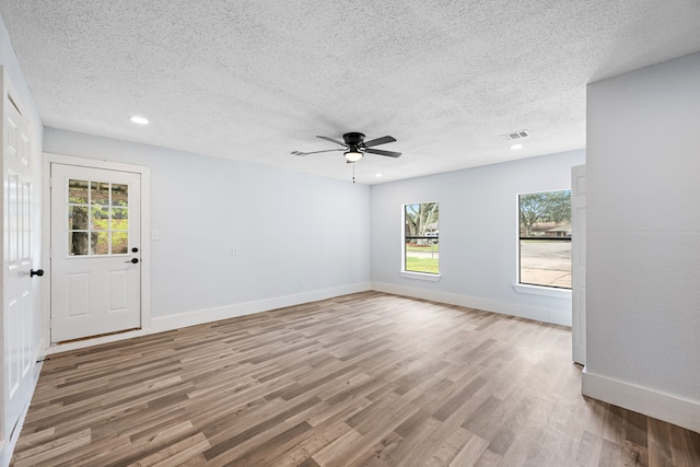 empty room with light wood-type flooring, a textured ceiling, and ceiling fan