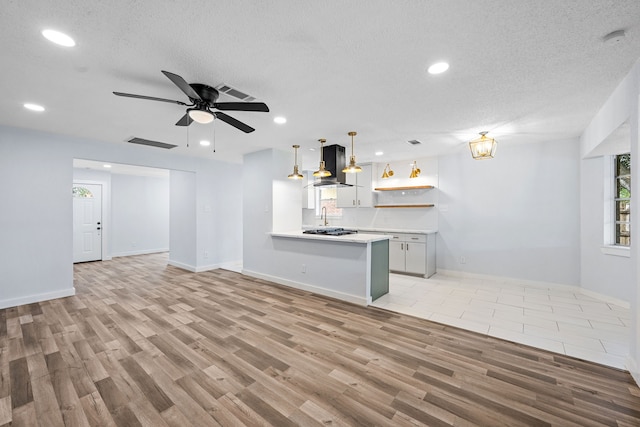 unfurnished living room featuring light hardwood / wood-style floors, ceiling fan, a textured ceiling, and sink