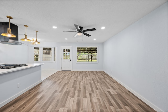 unfurnished living room with a wealth of natural light, ceiling fan, and light wood-type flooring